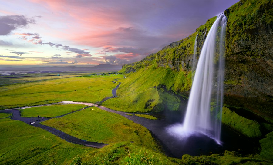 Cascada cayendo sobre un valle verde en Islandia