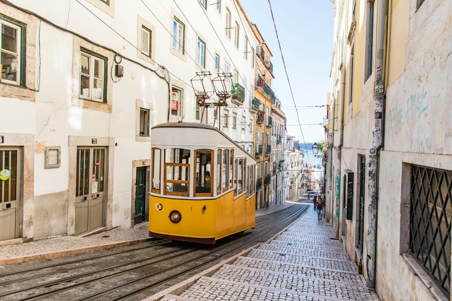 Tranvía amarillo recorriendo una calle empedrada de Lisboa