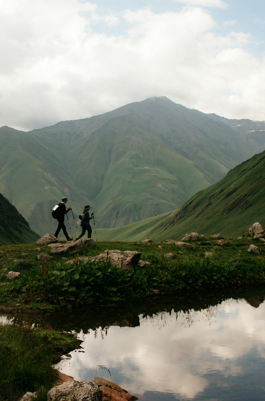 Dos excursionistas caminando por un valle verde de montaña